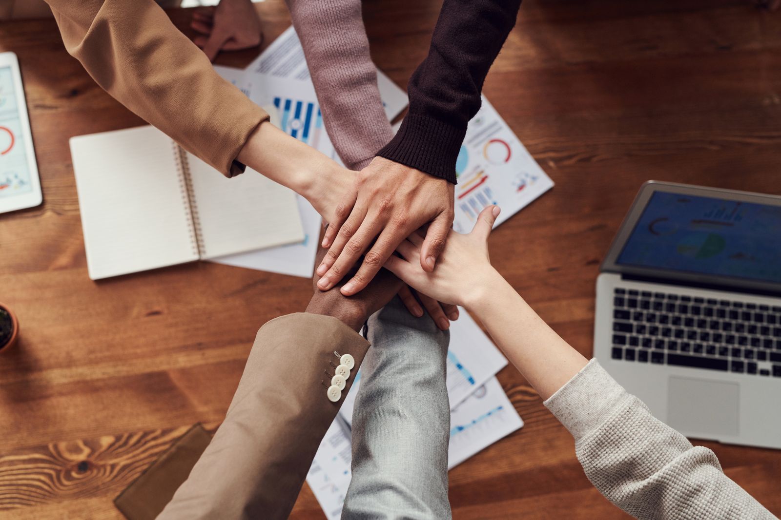 A team joining hands over their work